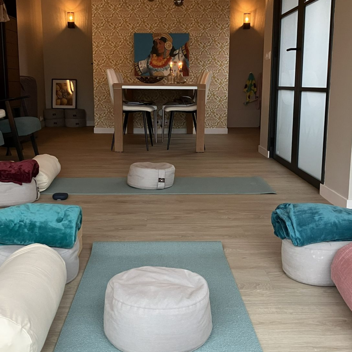 Yogastudio met matten, kussens, dekens en een tafel met stoelen.