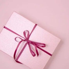 Roze geschenkdoos met een kastanjebruin lint op een roze achtergrond.