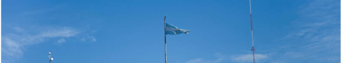 Uma bandeira azul tremula ao vento contra um céu azul.
