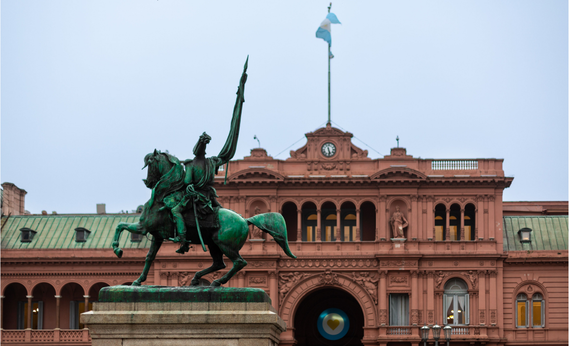 Uma estátua de um homem montado num cavalo em frente a um grande edifício.