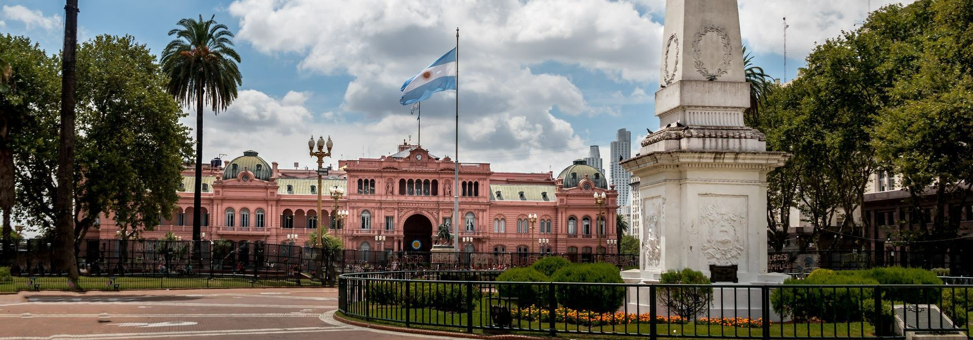 Um grande edifício rosa com uma estátua na frente.