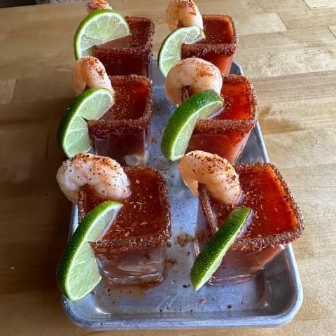 a tray of shot glasses filled with shrimp and lime slices