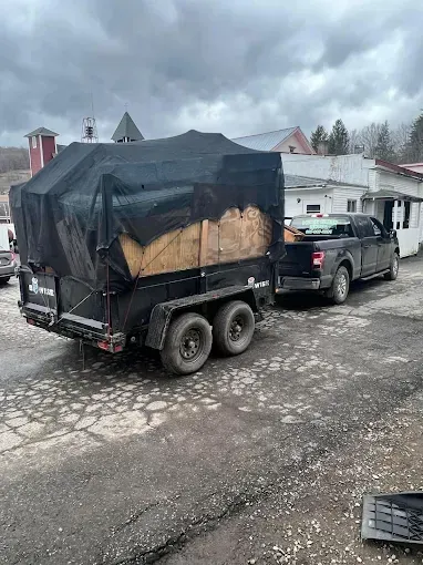 A truck is pulling a trailer with a tarp on it.