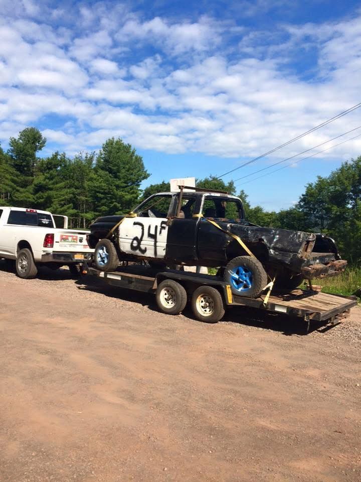 Two trucks are towing a race car on a trailer.