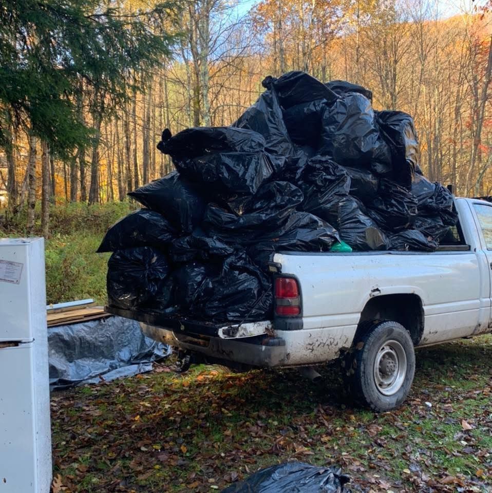 A white truck is loaded with black garbage bags