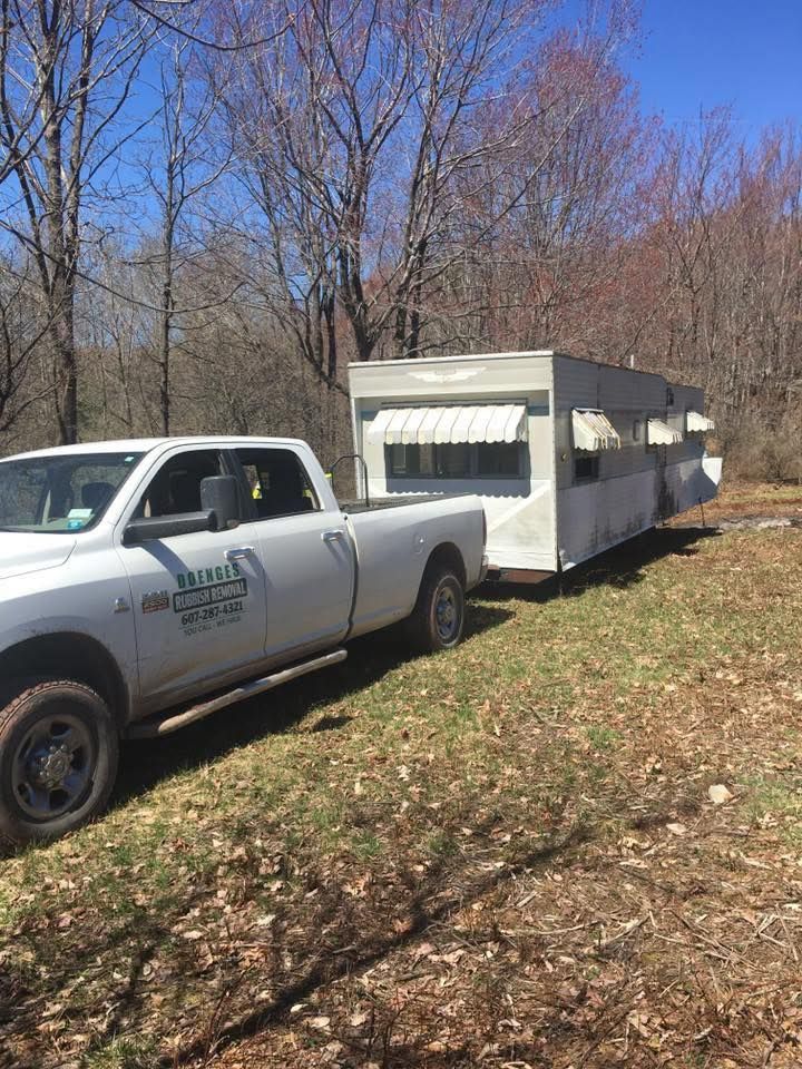 A white truck is towing a trailer in a field.
