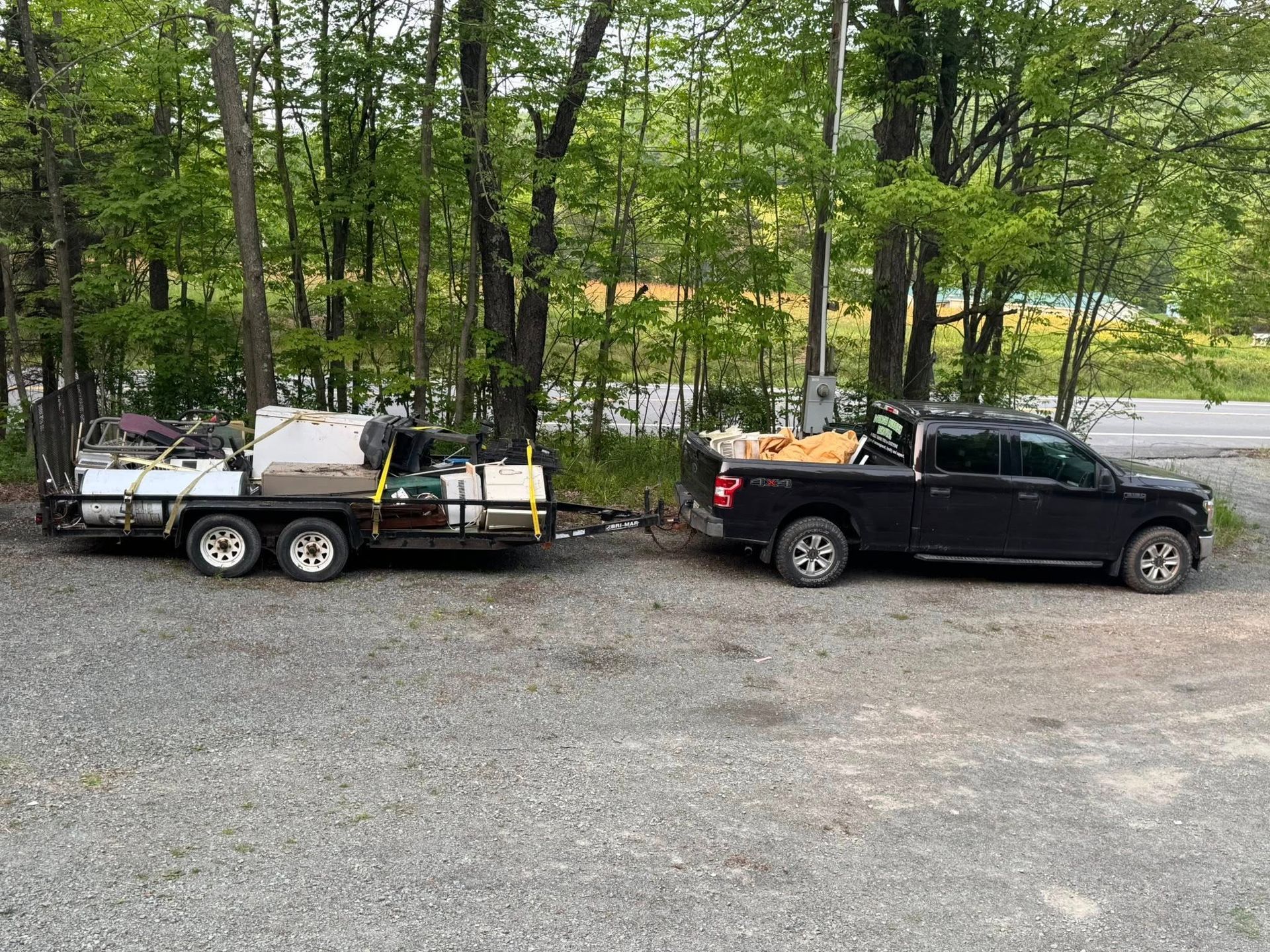 Two trucks are parked next to each other in a gravel lot.