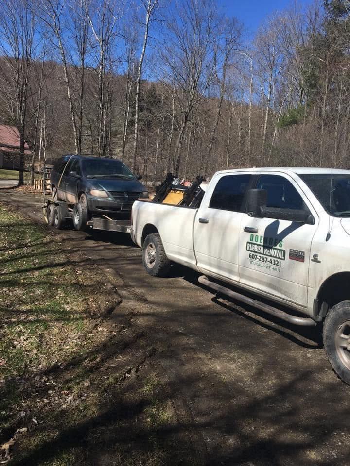 A tow truck is towing a car on a dirt road.