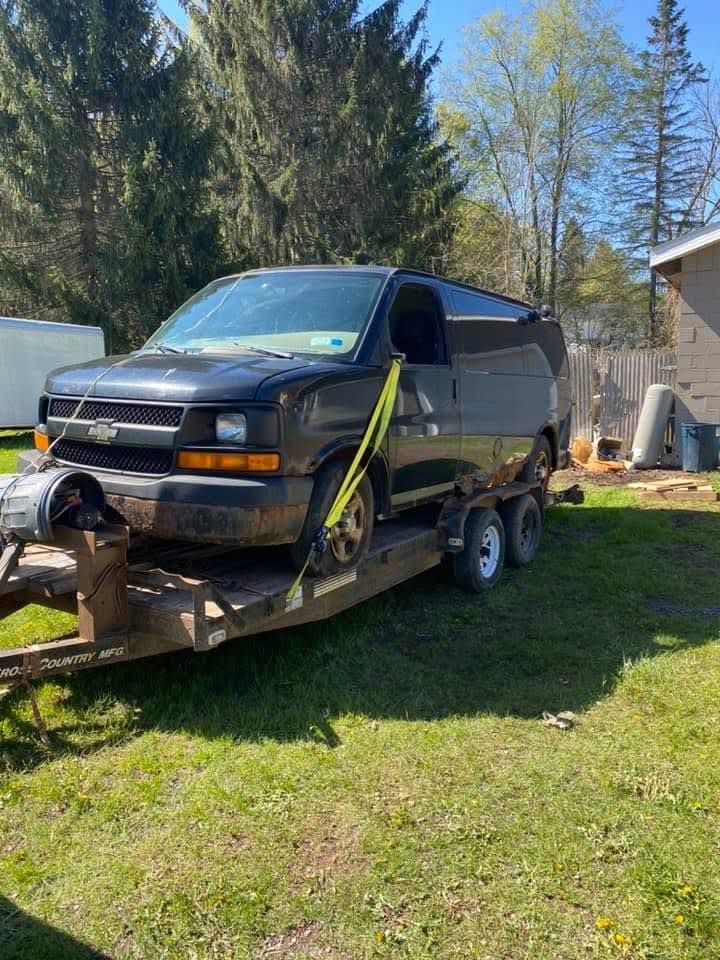 A black van is sitting on top of a trailer.