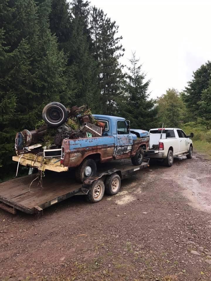 A blue truck is being towed by a white truck on a trailer.