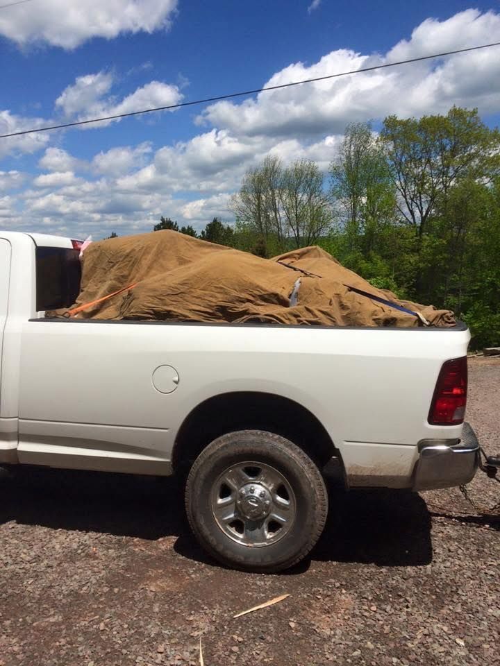 A white truck with a large pile of dirt in the bed.