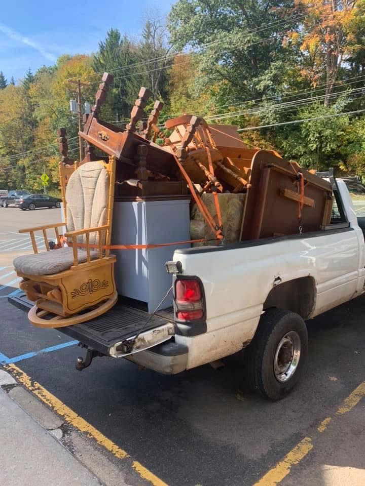 A white truck is filled with furniture and a rocking chair.