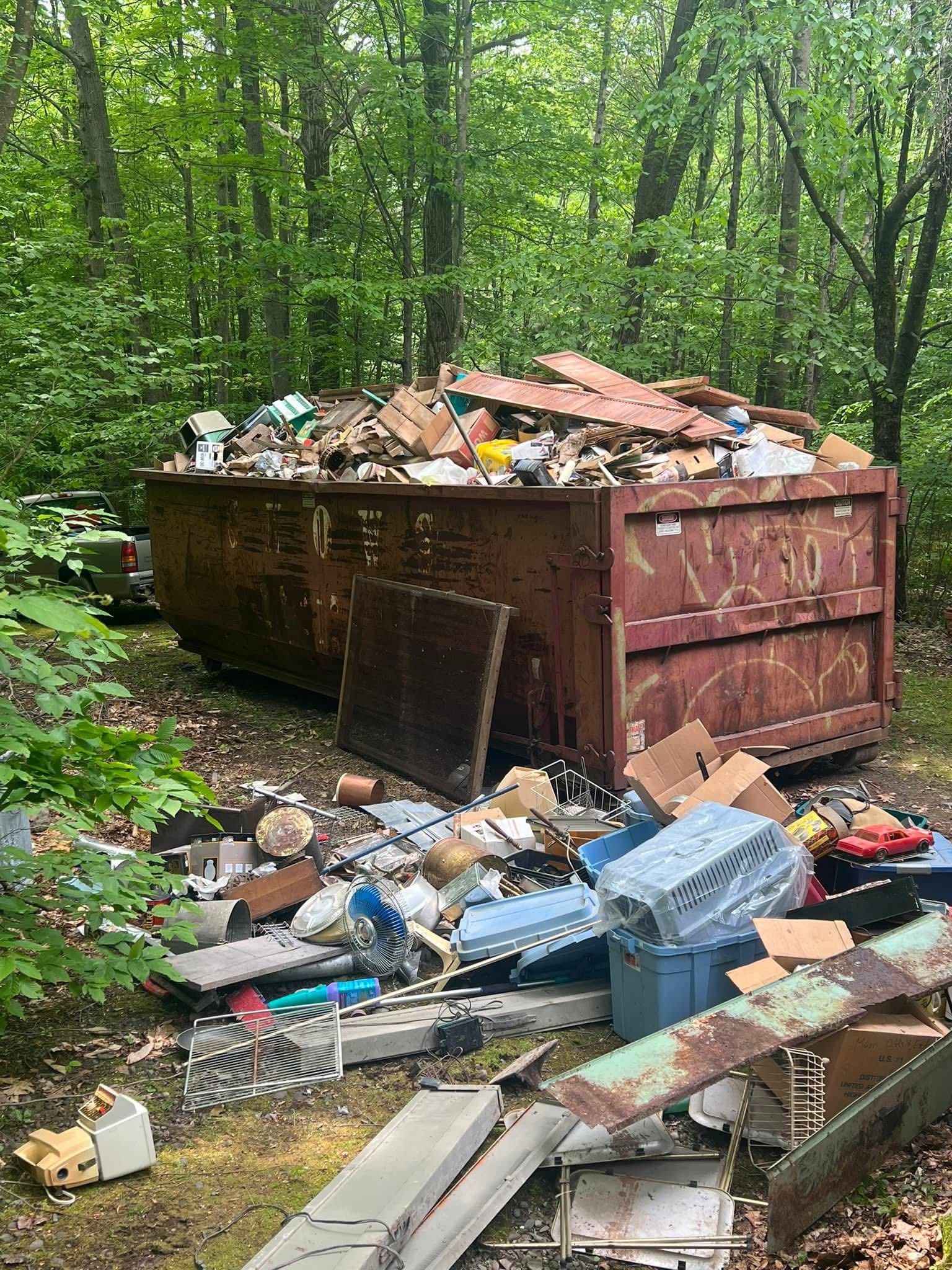 A dumpster filled with trash in the middle of a forest.