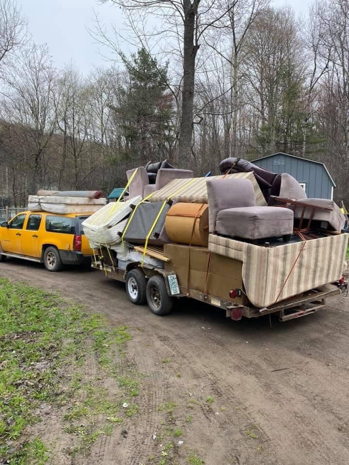 A yellow truck is towing a trailer filled with furniture.