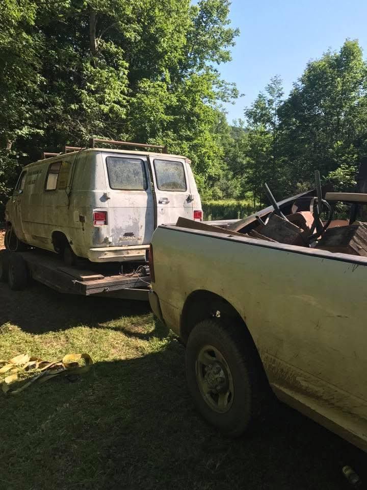 A white van is being towed by a white truck.