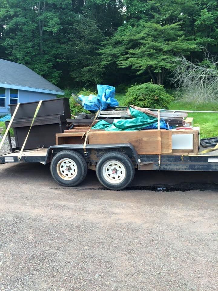 A trailer with a piano on it is parked in front of a house.