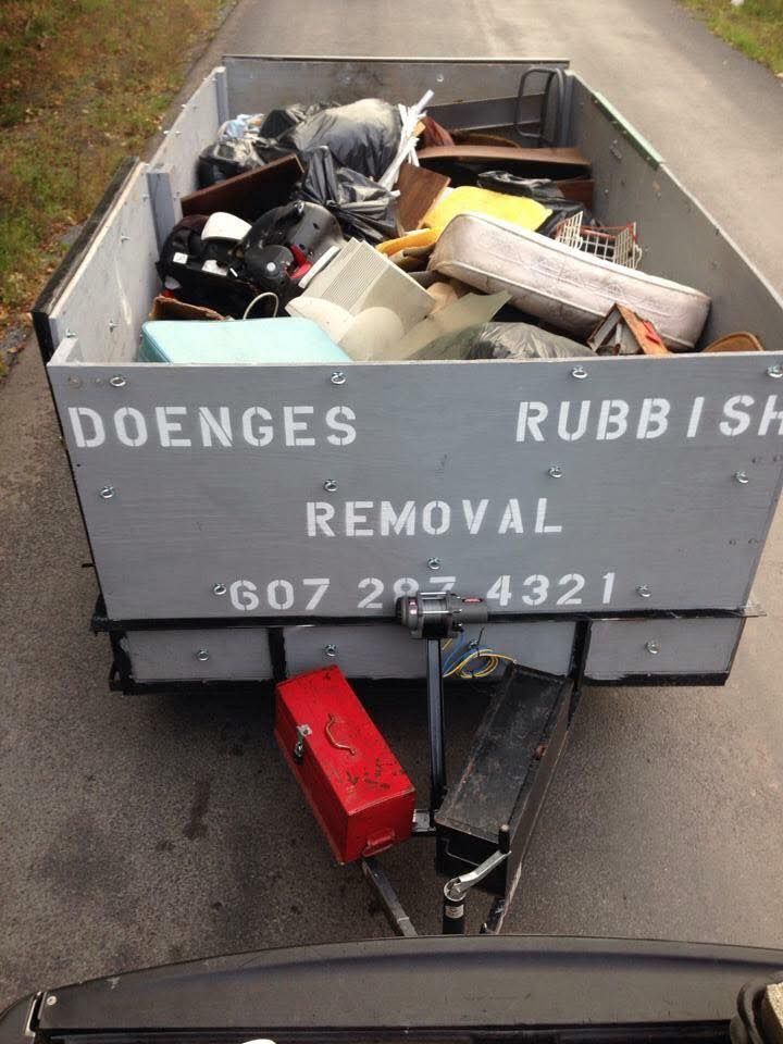 A trailer full of rubbish is being pulled by a car