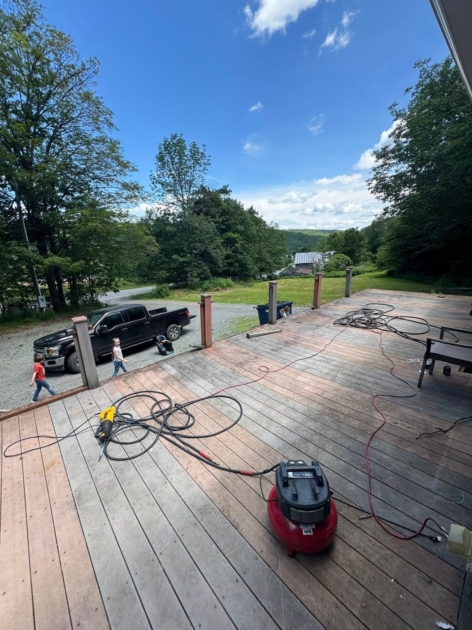 A vacuum cleaner is sitting on a wooden deck next to a truck.