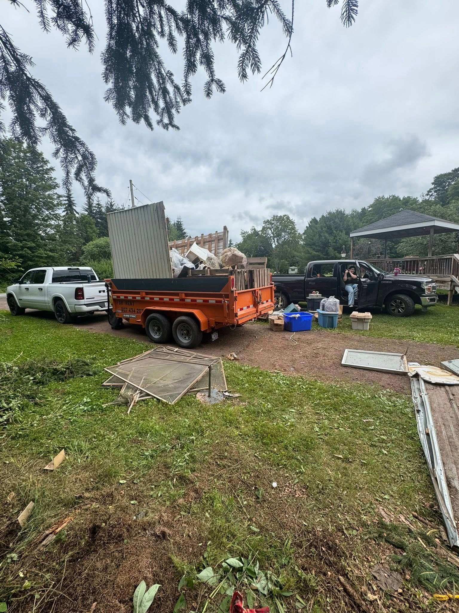 A truck is pulling a trailer full of junk in a yard.