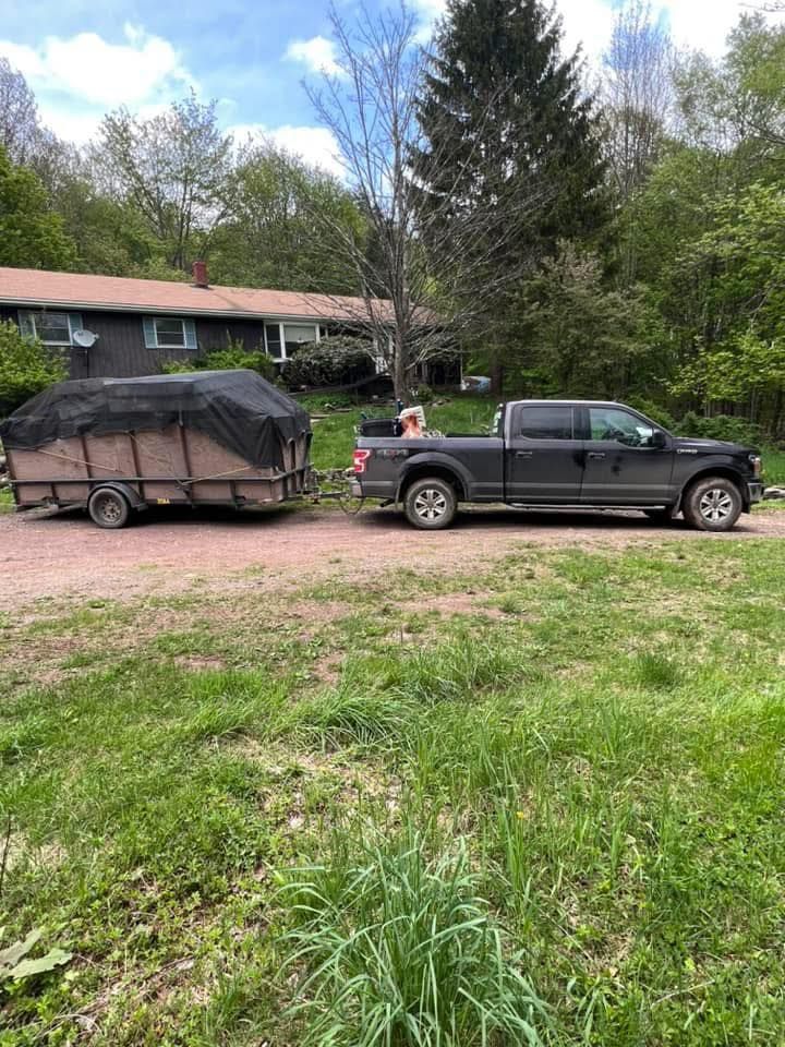 A black truck is towing a trailer in a grassy field.