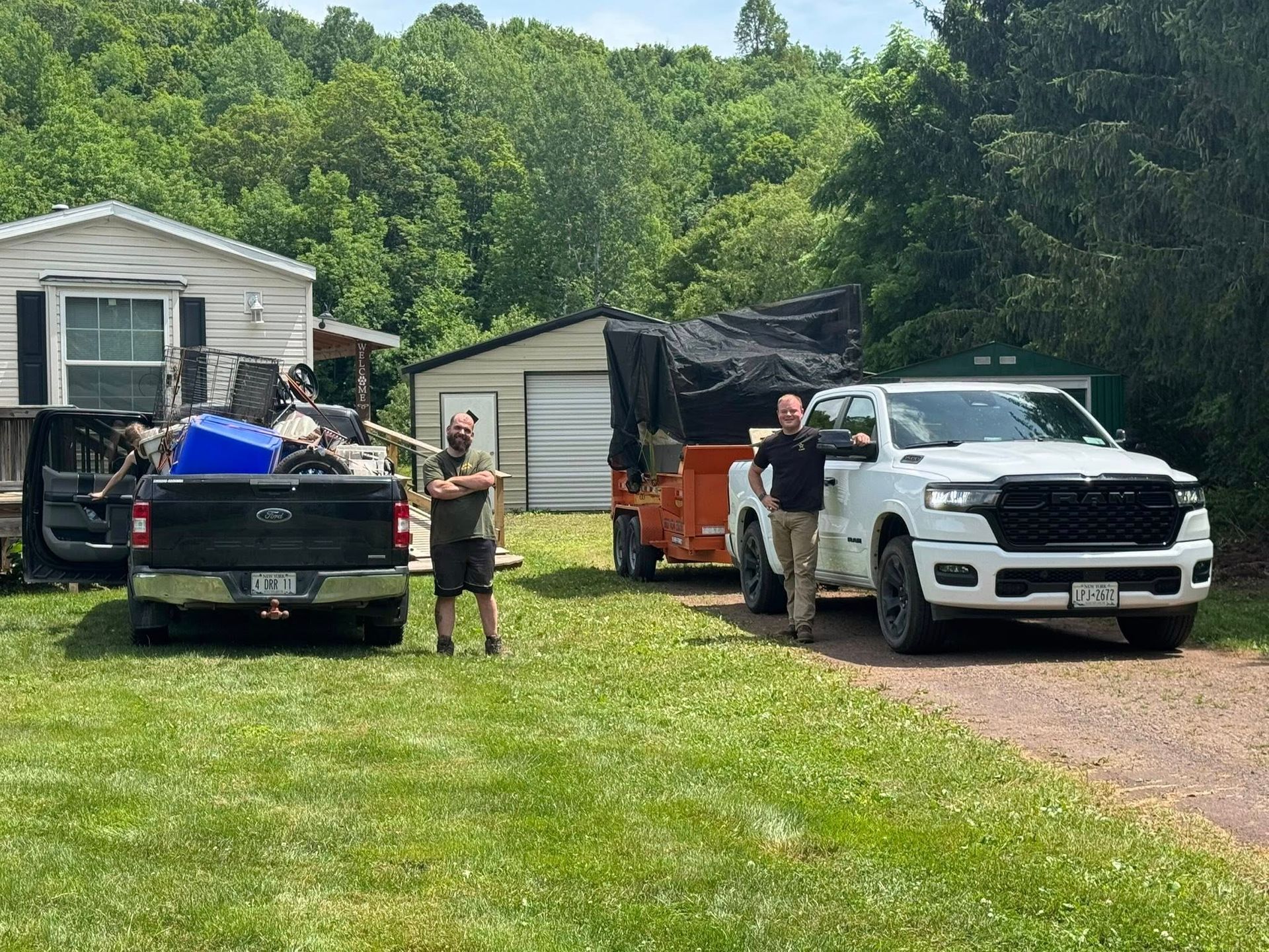 A couple of men are standing next to a truck in a yard.