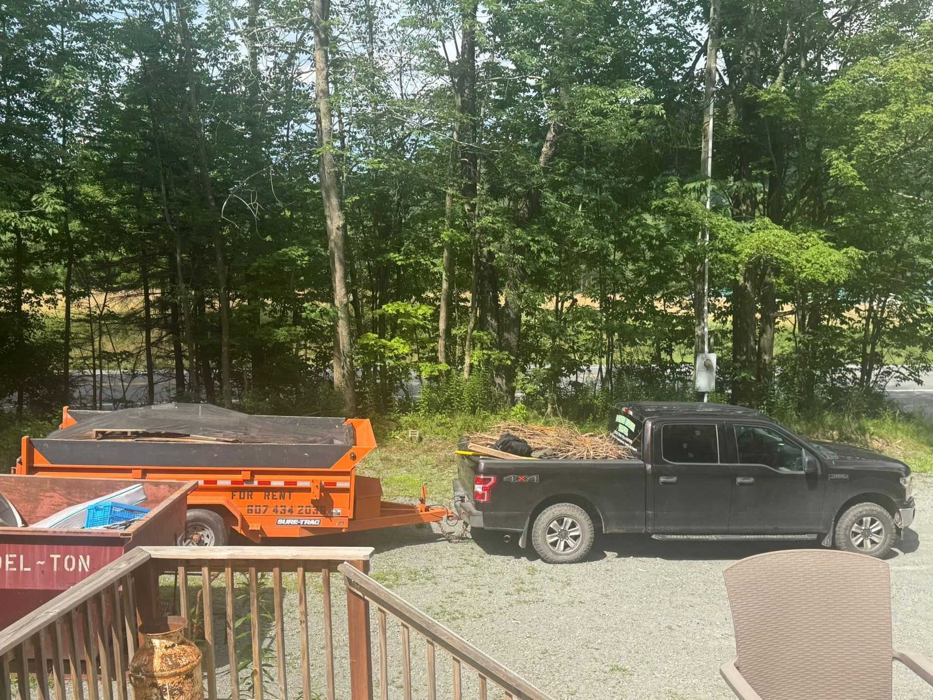 A truck is towing a dumpster on a trailer.