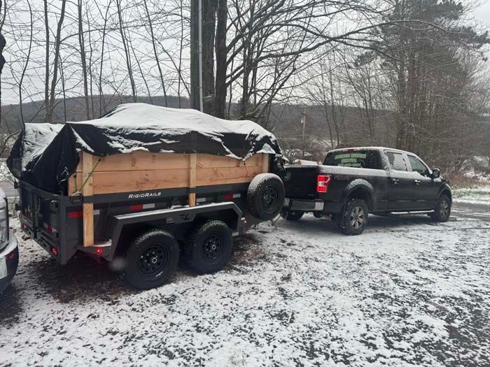 Red dumpster overflowing with trash in a wooded area; debris scattered around the base.
