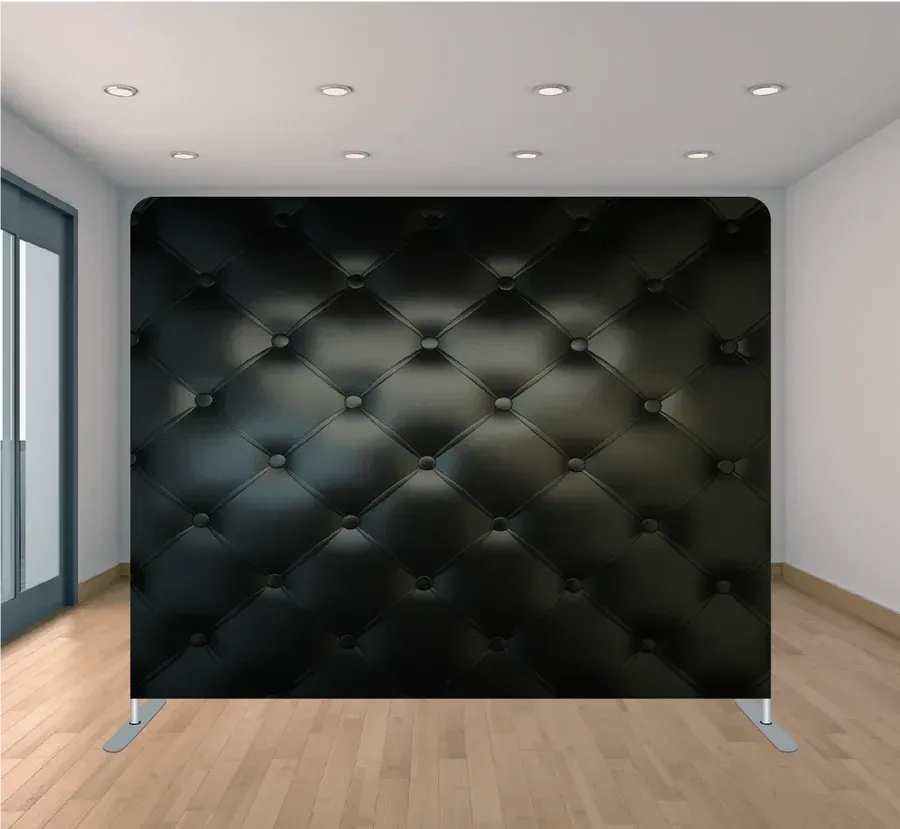 There is a black quilted wall in the middle of a room.