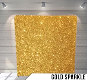 A gold sparkle backdrop is sitting in front of a white brick wall.
