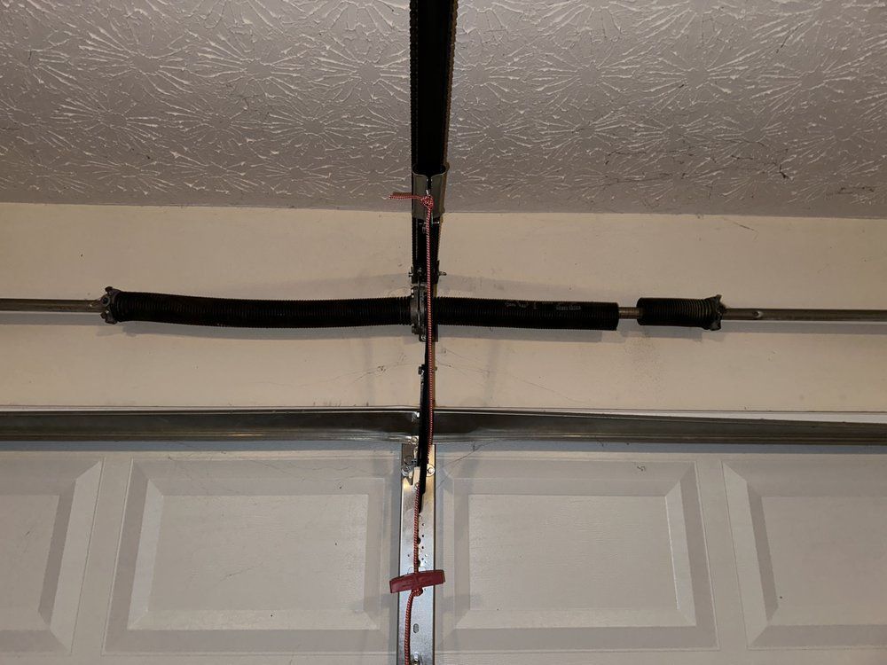 A close up of a garage door spring hanging from the ceiling.