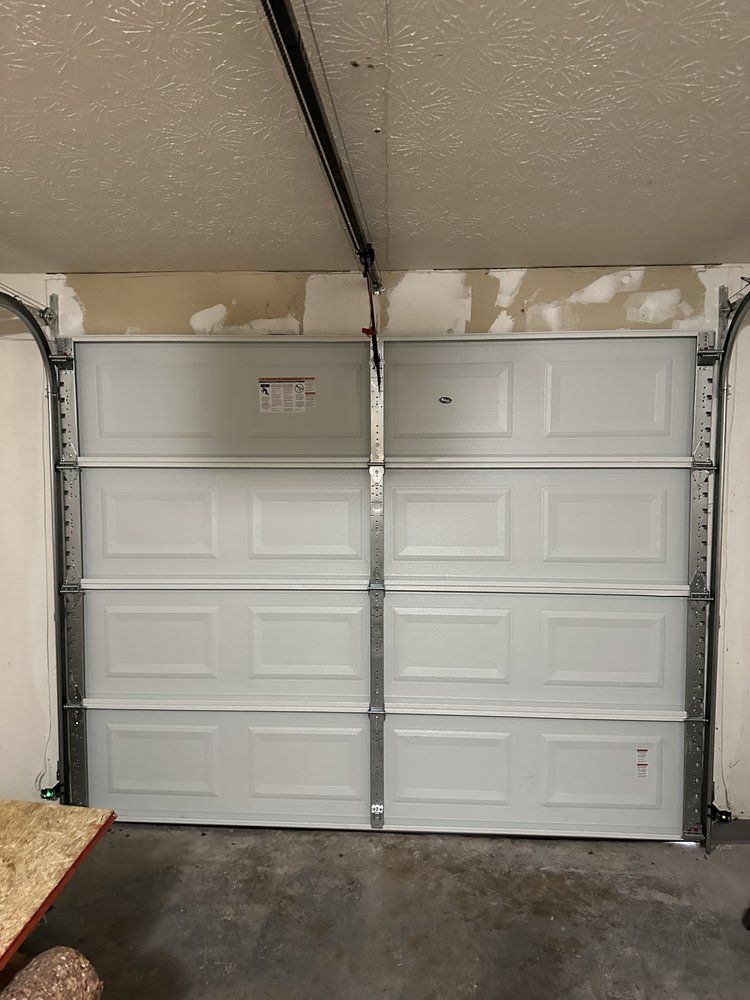 A white garage door is open in a garage.