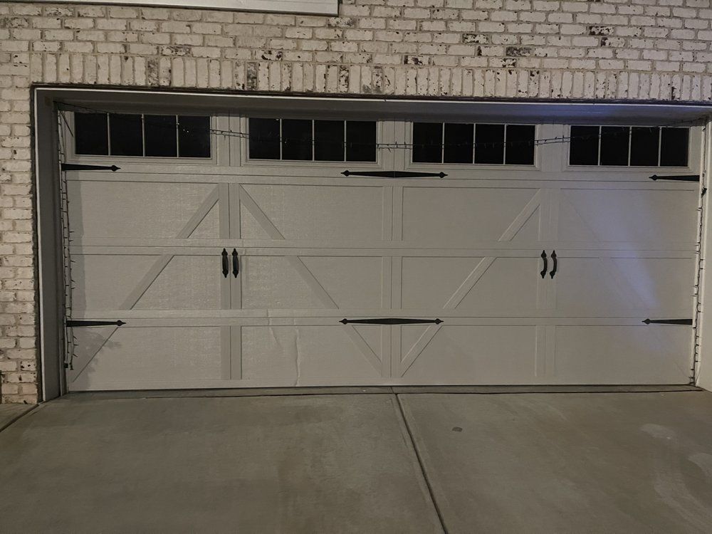 A white garage door is sitting in front of a white brick building.