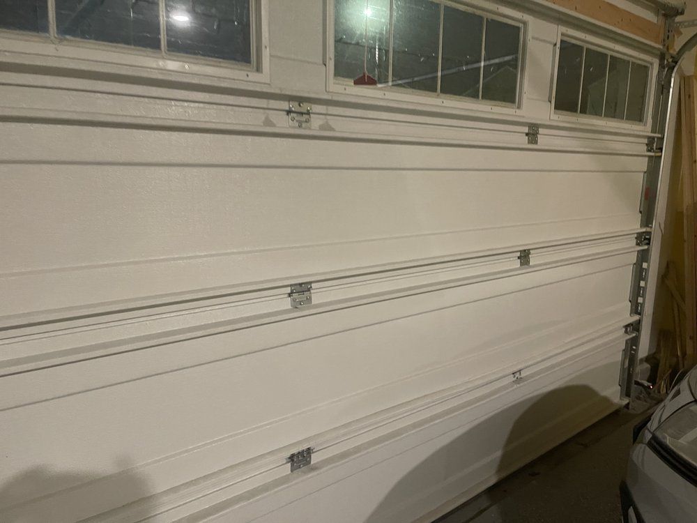 A white garage door with a car parked in front of it.