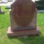 A gravestone is sitting in the grass in a cemetery.