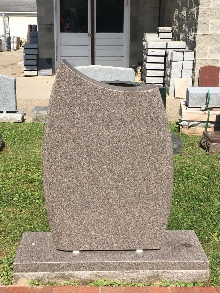 A gravestone is sitting in the grass in front of a building