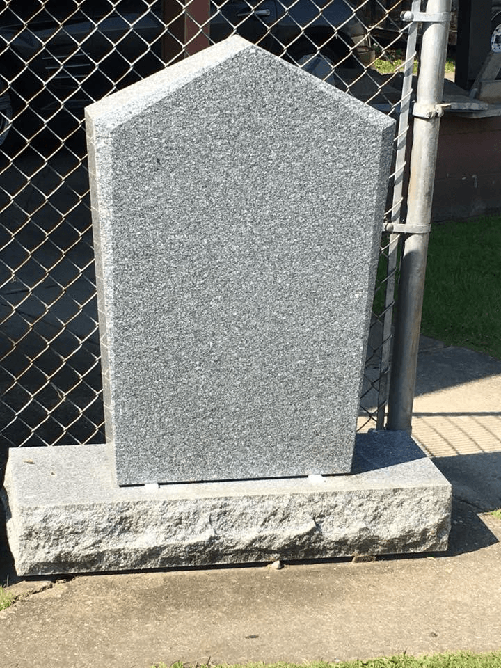 A gravestone is sitting in front of a chain link fence