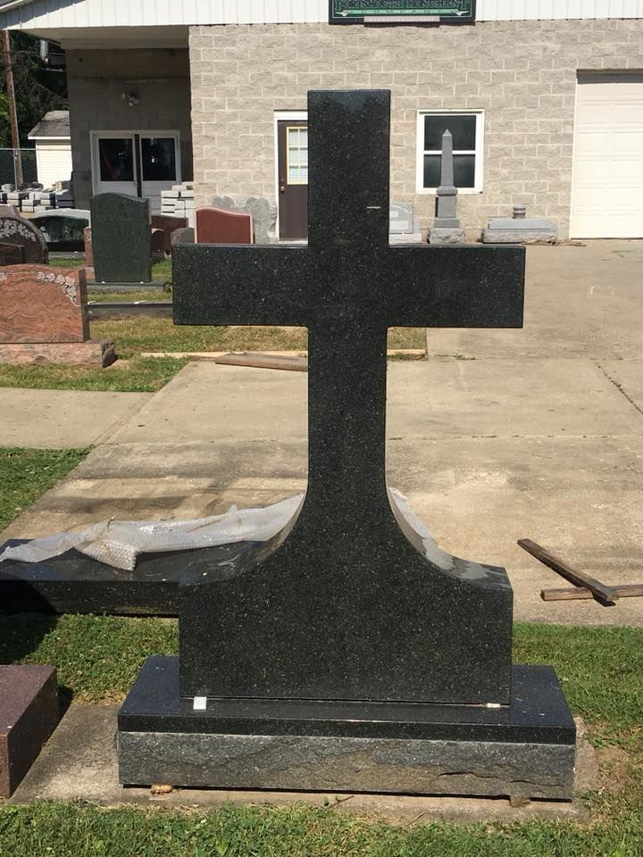 A black granite cross is sitting in front of a brick building