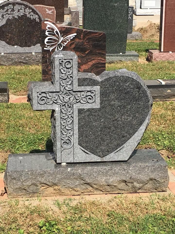 A gravestone with a cross and a heart on it in a cemetery.