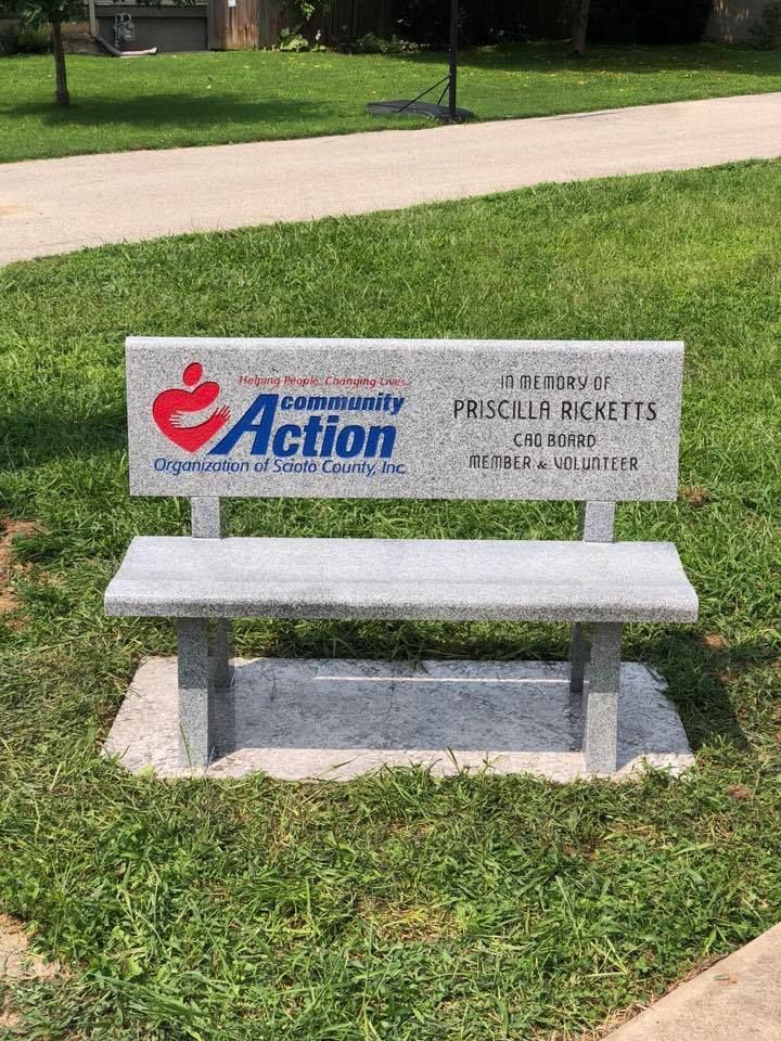 A concrete bench is sitting in the grass in a park.