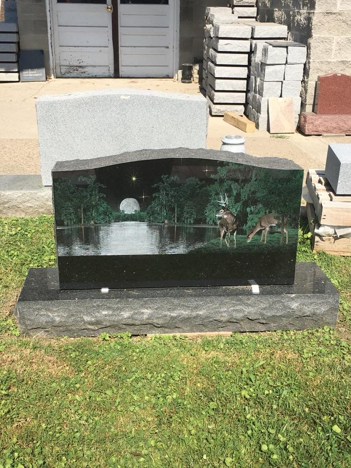 A gravestone with a picture of deer and trees on it