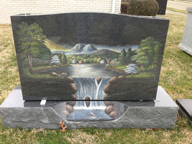A gravestone with a painting of a waterfall on it