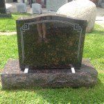 A gravestone is sitting on top of a concrete base in the grass.