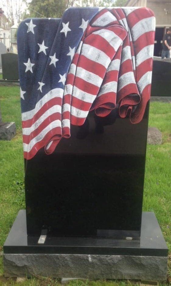 A black gravestone with an american flag draped over it