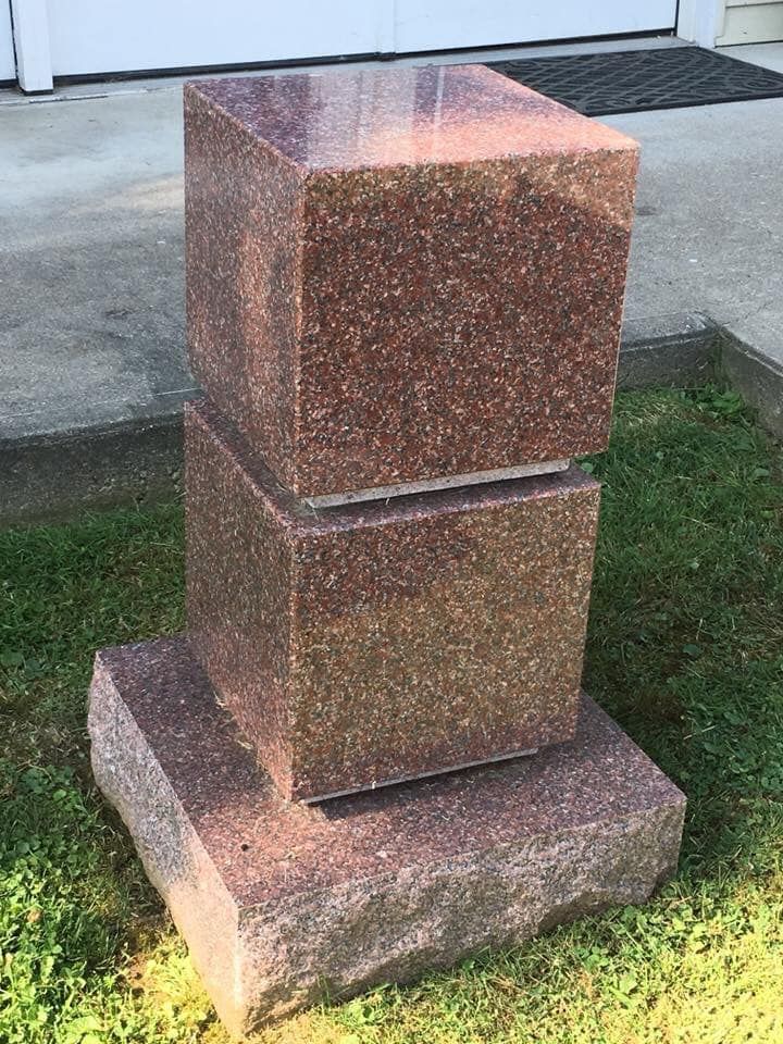 A stack of granite blocks sitting on top of each other in the grass.