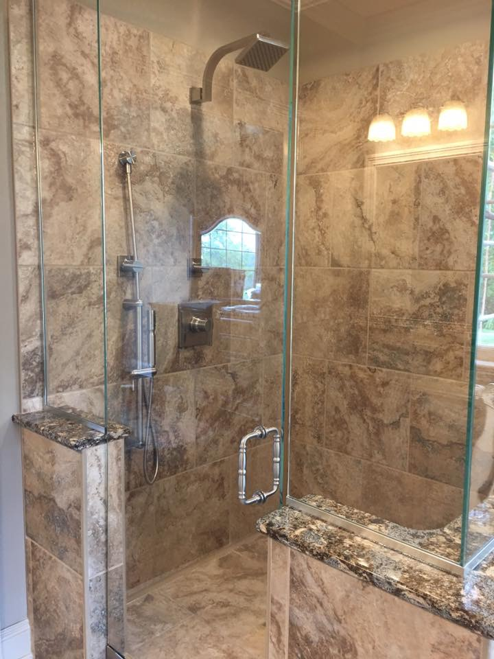 A bathroom with a walk in shower with a glass door.