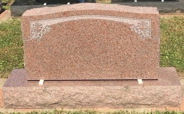 A gravestone is sitting in the grass in a cemetery.