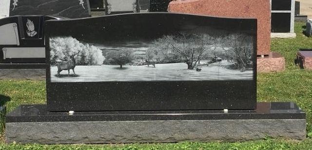 A gravestone in a cemetery with a picture of a field and trees on it.