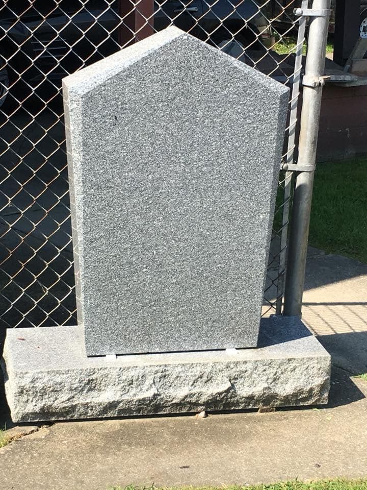 A gravestone is sitting in front of a chain link fence