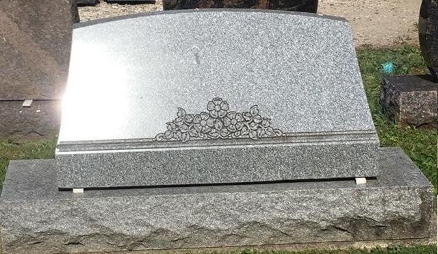 A gravestone is sitting on top of a grave in a cemetery.