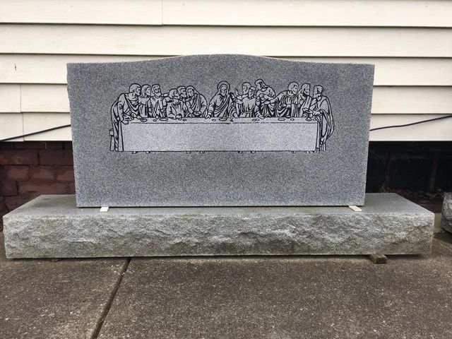 A gravestone with a picture of the last supper on it.